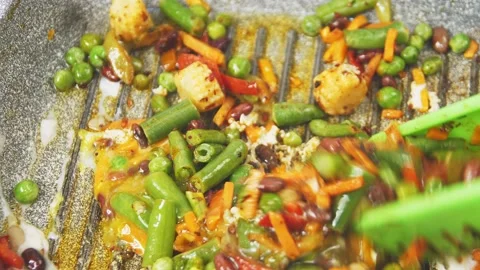 Frozen vegetables fried in a frying pan in oil are mixed with tongs. Stock Footage 168763952