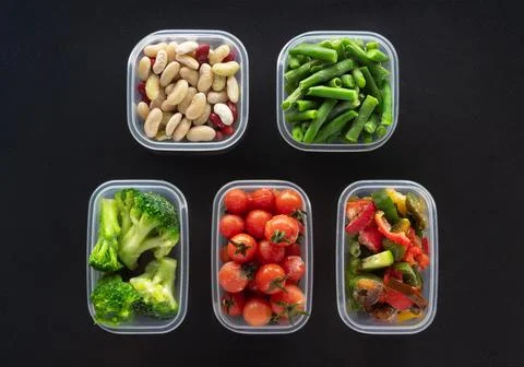 Frozen vegetables in plastic containers on black background. Foto stock