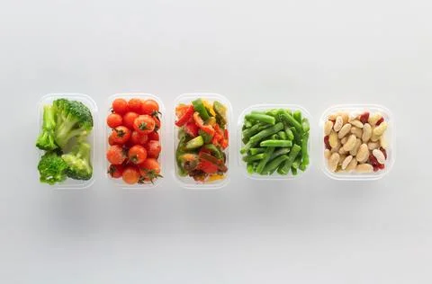 Frozen vegetables in plastic containers on white background. Stock Photos