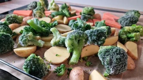 Frozen vegetables ready for cooking on a baking tray in a kitchen setting Stock Photos