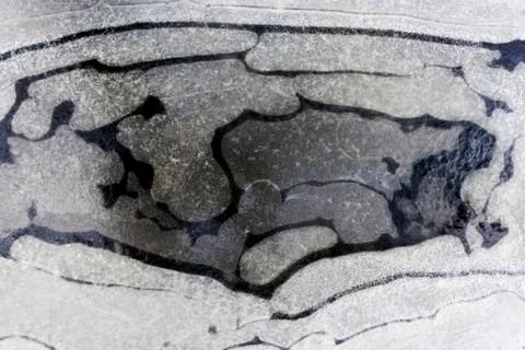 Frozen water in a puddle in winter. Stock Photos