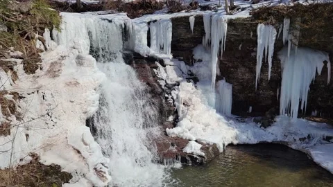 Frozen Waterfall flowing through icy winter surroundings Stock Footage 165478379