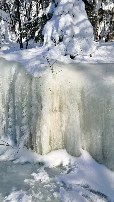 Frozen waterfall with icicles and snow in a winter forest. Stock Footage 347325882