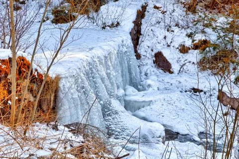 Frozen waterfall of mountain stream in the middle of snow and rocks on Dolomi Stock Photos