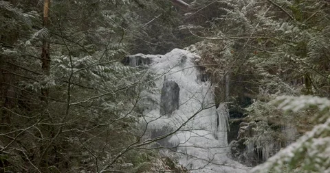 Frozen waterfall snow falling in forest in February Stock Footage 148609542