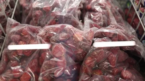 Frozen whole strawberries packed in clear bags and stored inside a freezer Stock Footage 345979027
