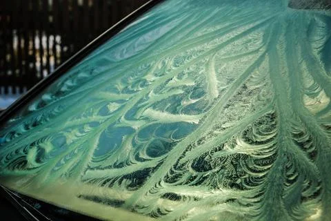 The frozen window of a car in cold winter day. Frost pattern. Selective focus Stock Photos
