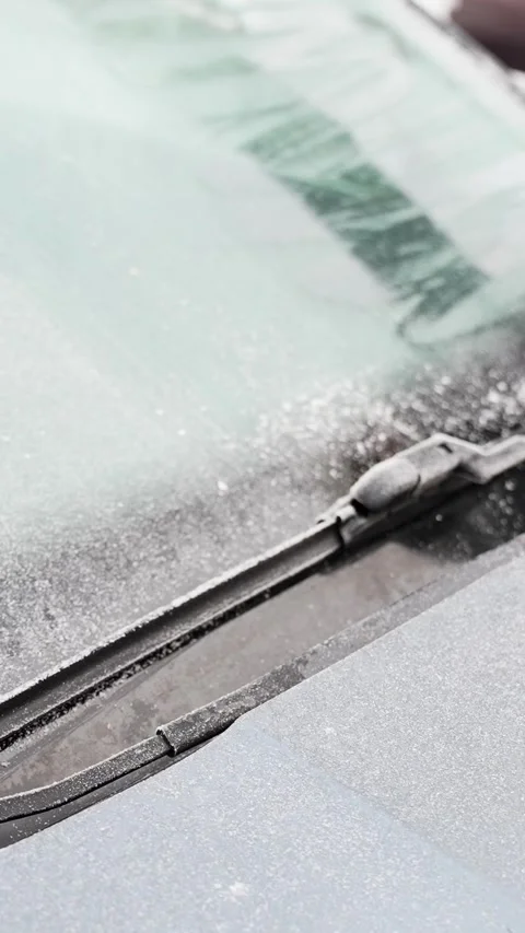Frozen windshield wiper and icy glass as a gloved hand clears frost with a snow Stock-Footage 327829971