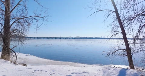 Frozen Winter Landscape with a Bridge Over a Partially Icy River Stock Footage 299949520