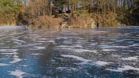 Frozen winter pond with thin icy surface covered by scattered frost patches Stock Footage 336904403