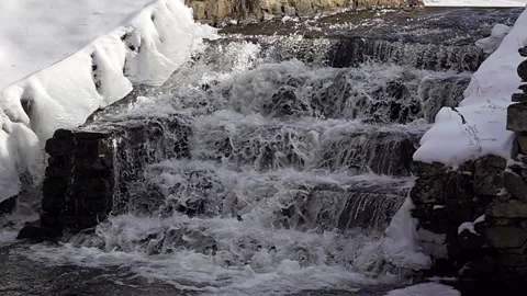 Frozen winter waterfall over rock steps from right side in slow motion Stock Footage