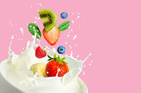 Fruit and bery mix falling into the bowl with milk and splashing on a pink Stock Photos