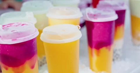Fruit bubble tea cups standing on ice, outdoor street food market Stock Footage 343058991