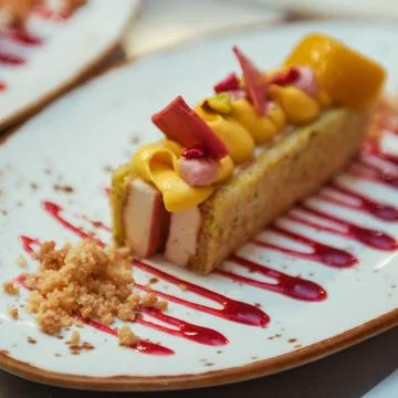 Fruit cake with orange, mango and strawberry sauce on a white plate Stock Photos