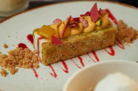 Fruit cake with orange, mango and strawberry sauce on a white plate Stock Photos