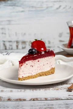 Fruit cake slice. Cheesecake slice with blackberry sauce on wood background.  Stock Photos