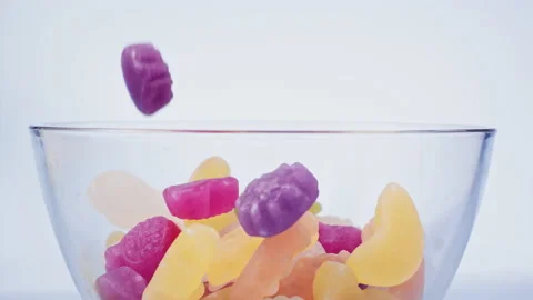 Fruit candy s fall into a bowl on blue background super slow motion 1000 fps Stock Footage 141052186