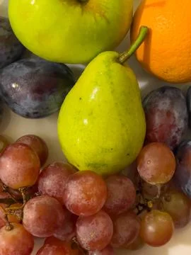 Fruit composition on a plate. Pear, grape, plum, orange Stock Photos