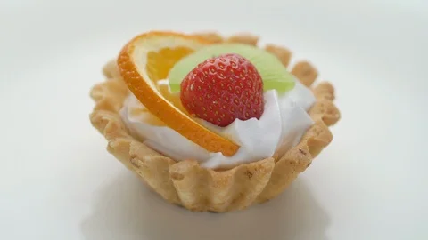 Fruit dessert tart with whipped cream, strawberry and kiwi on white plate Stock Footage 110901477