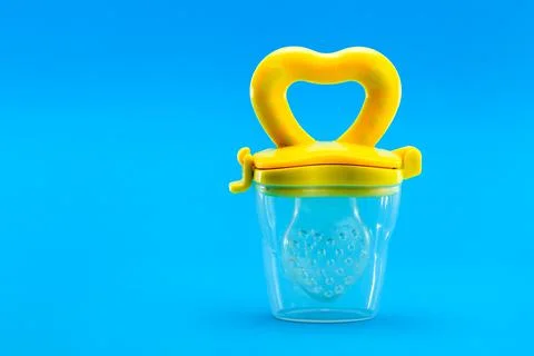 Fruit feeder for feeding weaned babies isolated on a blue. Stock Photos