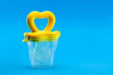 Fruit feeder in a plastic case with a yellow handle and a silicone pacifier. Stock Photos