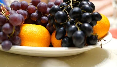 Fruit on the festive table. The two types of grapes and tangerines. Stock Photos