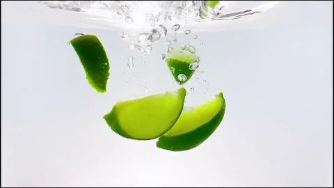 Fruit lime slice splash falling down into white cocktail and water Stock Footage 76199462