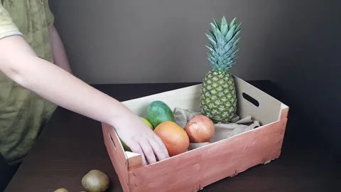 Fruit packaging wooden gift box. a man packs a gift of pineapple mango kiwi on a Stock Footage 168821250