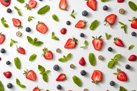Fruit pattern with half strawberries, blueberries and mint leaves on a white Stock Photos