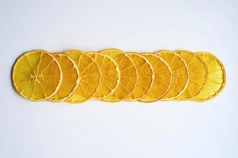 Fruit pattern of a row of dried orange slices centered on a white background Stock Photos
