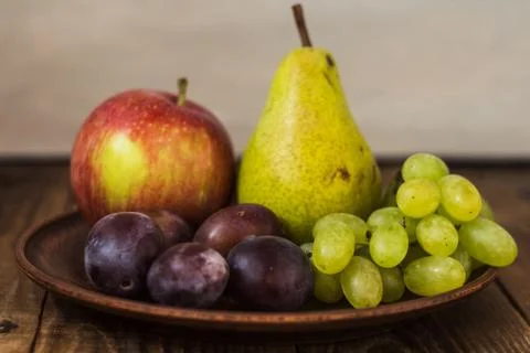 Fruit plate grapes apple plum pear Stock Photos