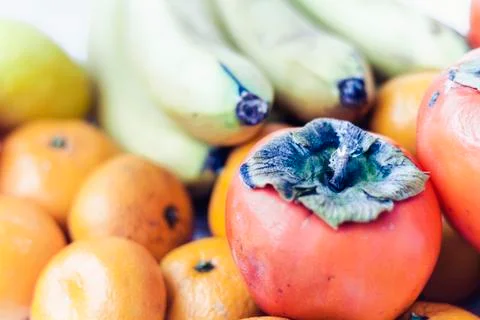 Fruit plate on white background. Mandarins, bananas, persimmons and lemons. Stock Photos