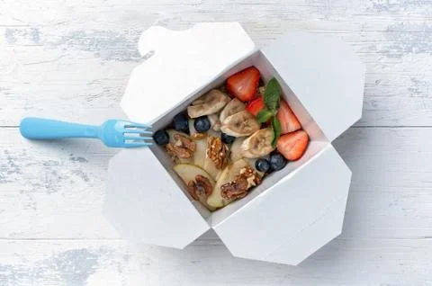 Fruit platter in paper box with plastic blue fork Stock Photos