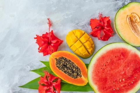 Fruit platter. Watermelon, melon, mango, papaya and flowers on background. Stock Photos