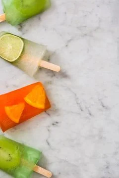 Fruit popsicles on white marble.. Stock Photos