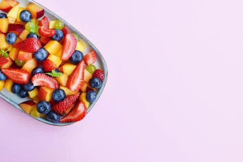 Fruit salad in a rectangular plate on a pink background. Sliced strawberries, Stock Photos