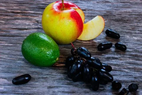 Fruit set. fresh lime, apple and grapes on a wooden surface. Stock Photos