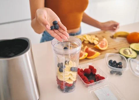 Fruit, smoothie and blender with hands of woman in kitchen for gut health, diet Stock Photos