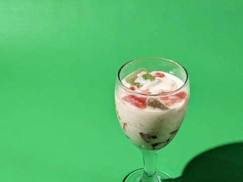 Fruit soup or mixed ice in a glass cup on a green background Stock Photos