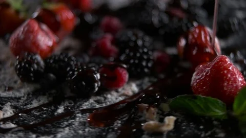 Fruit syrup poured closeup black background Stock Footage 69919977