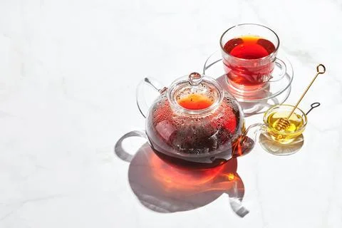 Fruit tea with apples and thyme and honey in glass teapot and cup on white Stock Photos