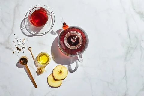 Fruit tea with apples and thyme and honey in glass teapot and cup on white Stock Photos