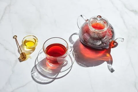 Fruit tea with apples and thyme and honey in glass teapot and cup on white .. Stock-Fotos