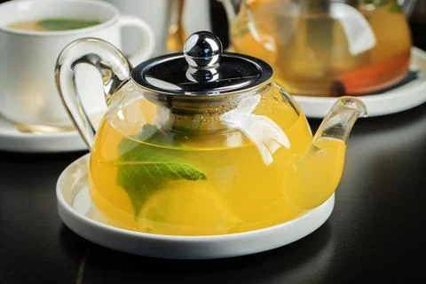 Fruit tea with mango and mint in a glass teapot on the table Фото
