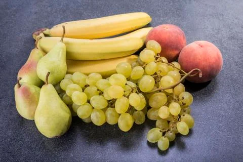 Fruit on top of the kitchen table grapes peaches bananas and pears Stock Photos