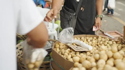 Fruit Vendor Handing Packaged Langsat Fruit to Customer at Local Market Stock Footage 341301279
