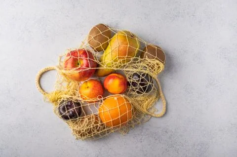 Fruits in the range in yellow eco string bag on a light wooden surface Stock Photos