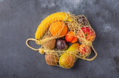Fruits in the range in yellow eco string bag on a dark wooden surface Stock Photos