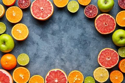 Fruits sliced mix frame flat lay on blue concrete background blank copy design Stock Photos