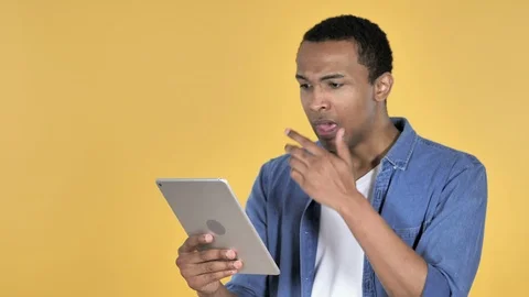 Frustrated African Man in Shock while Using Tablet Isolated on Blue Background Stock Footage 99014526
